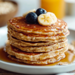 Tortitas de avena saludables servidas en un plato con frutas frescas y jarabe de arce.